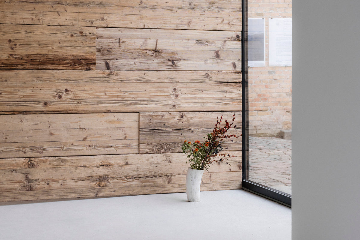 Wandverkleidung FACE aus Gerüstbohlen mit Blumen am Fenster