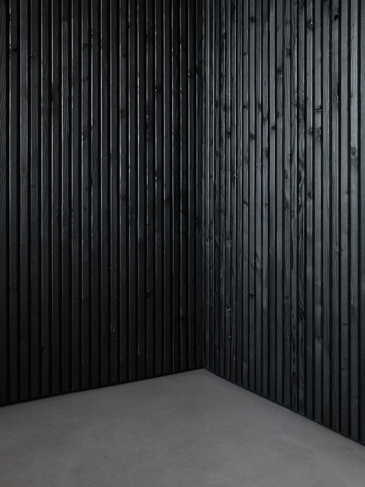 Schwarze Wandverkleidung aus Altholz im Raum